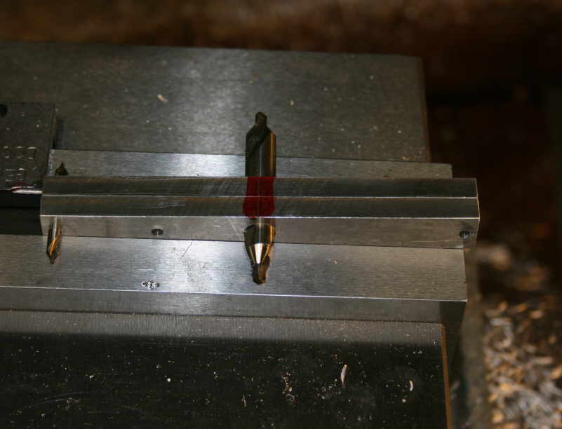 A metal beam with two small metal pieces attached to it in a workshop or factory setting.