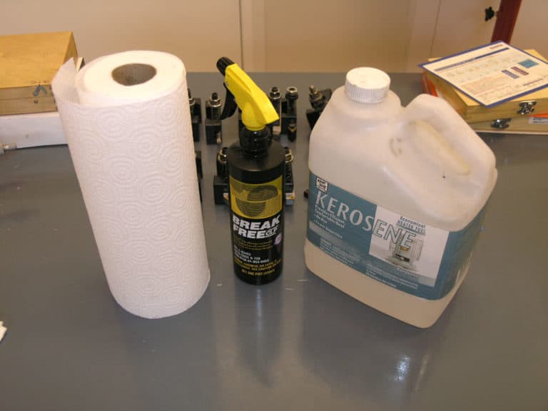 Machine shop tools and cleaning supplies arranged on a gray workbench.