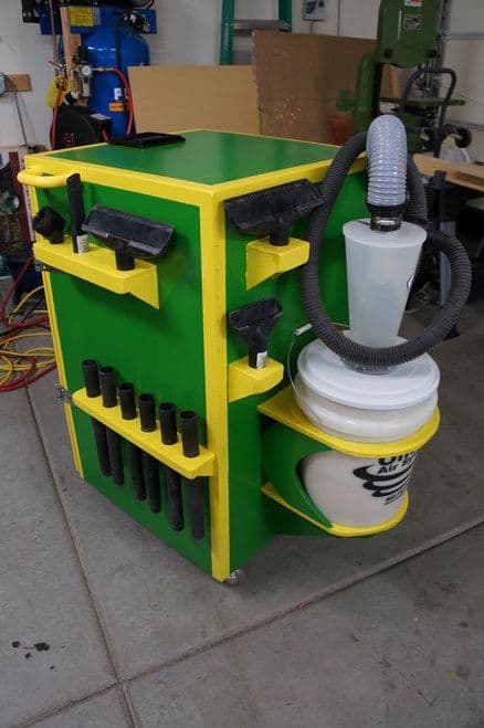 A green and yellow Shop Vac Station with attached hose, used in machine shops or fabrication environments.
