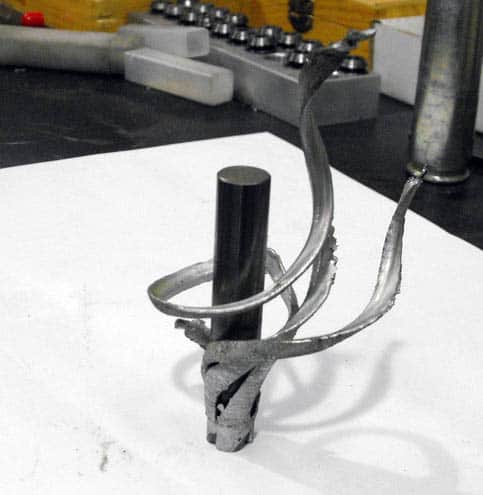 Metalworking tool with long rod and curved metal attachment.