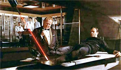 Man in black suit lying on his back, targeted by red laser beam.