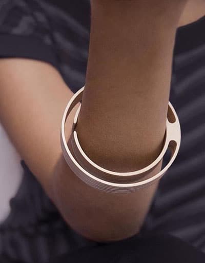 A silver metal bracelet with flat design, rounded edges, and uniform thickness on an arm.