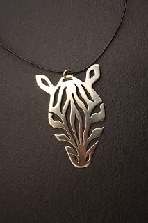 Close-up of cutout zebra head pendant on dark gray background.