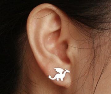 Woman's ear with dragon-shaped earrings.