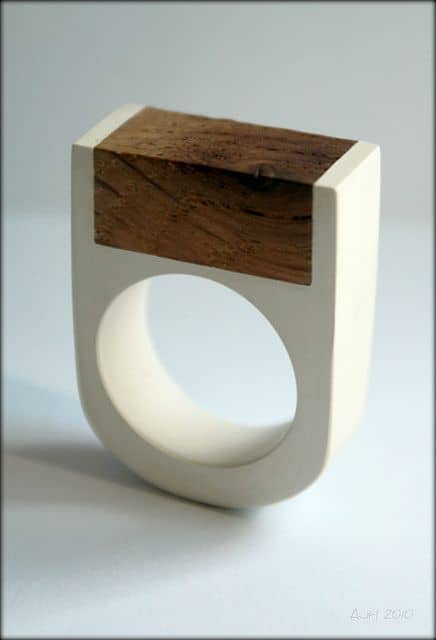 A modern ring with a white rectangular design featuring a circular hole and a small wooden or plastic top.