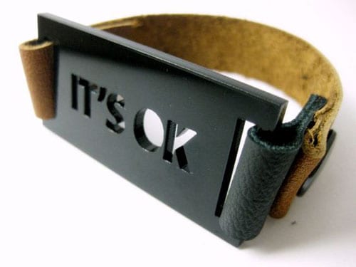 Laser-cut leather bracelet with 'IT'S OK' text in bold letters on a white background.