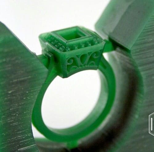 Green wax ring with intricate design used in lost-wax casting process.