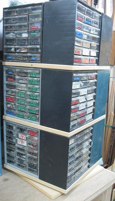 Tall metal storage cabinet with labeled drawers containing machinery components and tools.