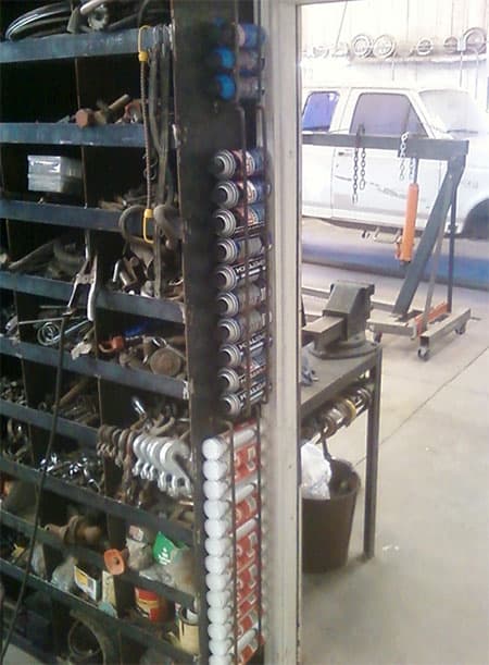 A spray can rack with a white van visible through its rear door.