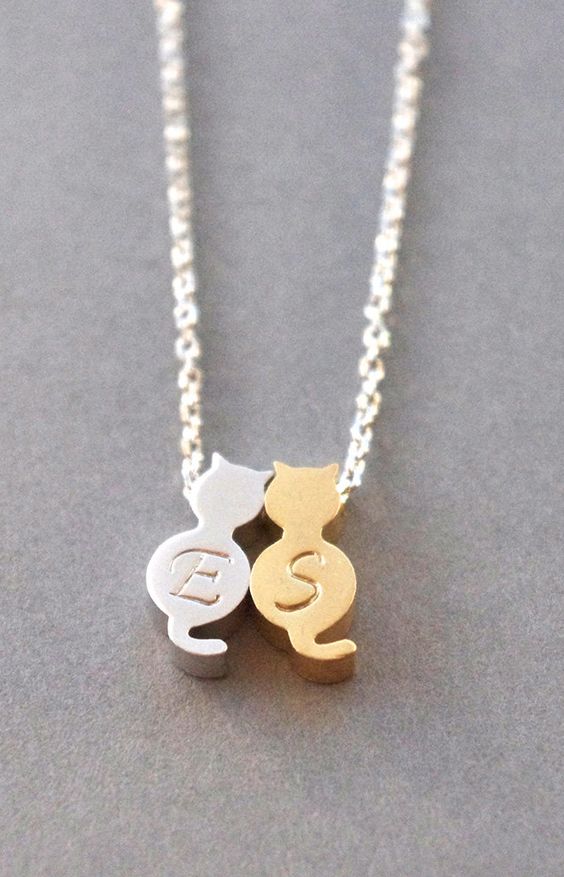 Silver and gold necklace with two cat-shaped pendants.