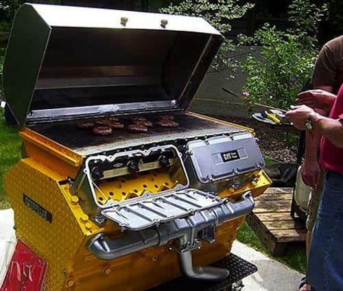 Yellow portable gas grill with three burgers on the grates.