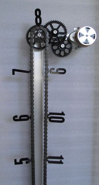Vertical metal rod with chained gears and painted measurement markings (5-8).
