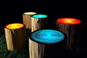 Three cylindrical logs with colored tops (yellow, teal, red) on a dark background.