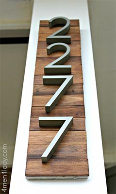 Large silver house number sign with "2227" on wooden background.