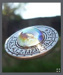 Oval-shaped sundial with engraved numbers and decorative markings.