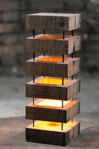 Wooden outdoor light fixture with stacked rectangular blocks and a soft yellow glow.
