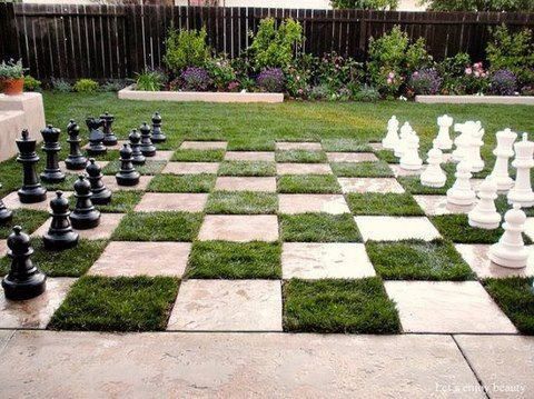 Oversized stone chess pieces on a grassy chessboard.