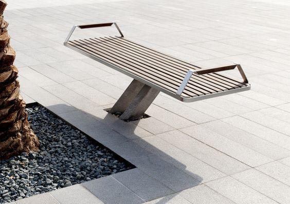 Sleek modern outdoor bench with slatted wooden seat on urban stone floor