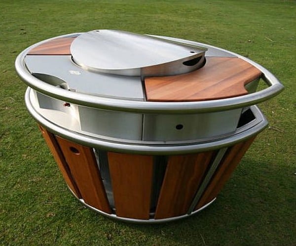 Large oval-shaped metal object with vertical slats and a shiny surface on a grassy lawn.