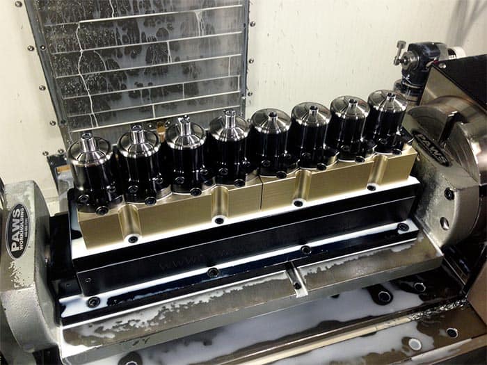 Black and silver collet chucks on a CNC tool turret with PAWS logo.