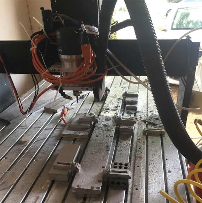Black metal CNC mill machine with components, cables and metal plates setup.
