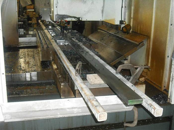 A rectangular part being machined on a CNC machine with a long, flat surface and straight edges.