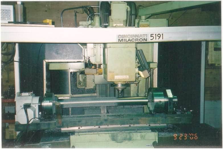 A large industrial Cincinnati Milacron 519 machine, in operational use, with cables and wires visible.