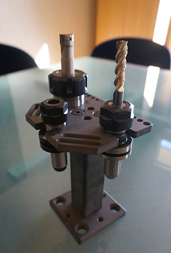 Industrial drill bit on metal base with cylindrical protrusion against blurred background.