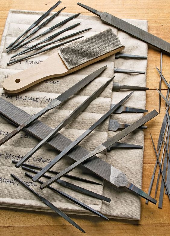 Various metalworking files and rasps laid out on a cloth.