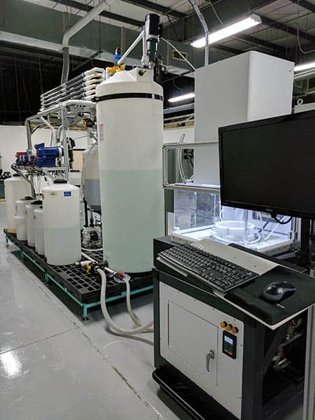 Large cylindrical tank with white exterior and black trim, connected to pipes and machinery in an industrial setting.