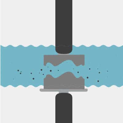 Stylized illustration of PECM process step three, a cylindrical tool submerged in light blue electrolyte solution with sparks flying off during metal removal from workpiece.