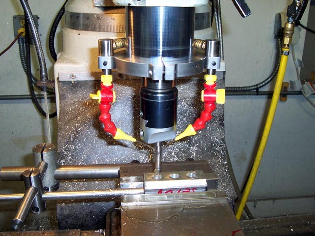 Metalworking machine in workshop setting with cylindrical component and red/yellow hose.