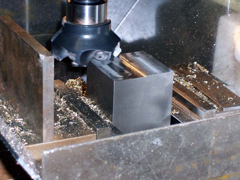 Milling machine work surface with dark grey base, silver metal piece and attached black component.
