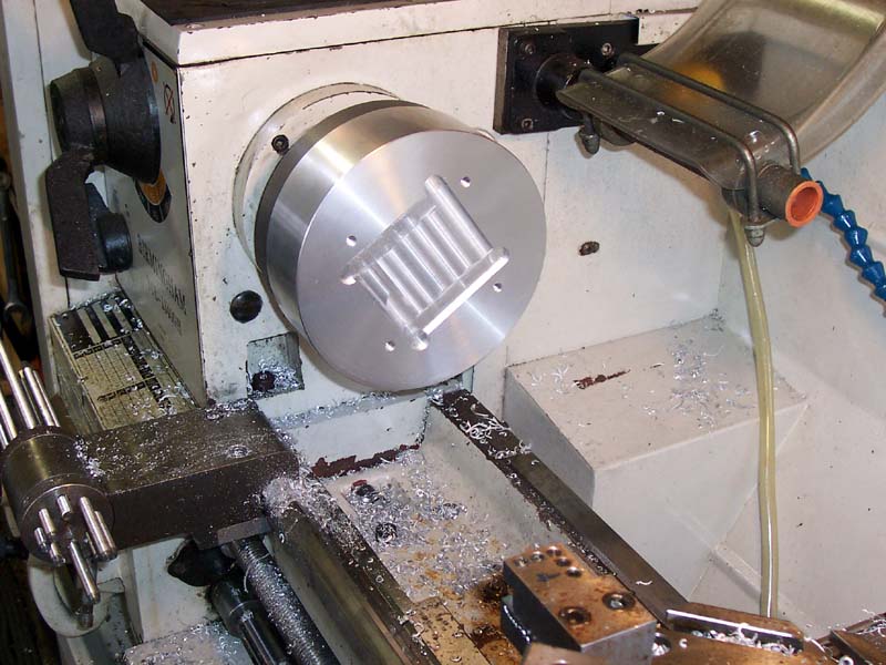 A lathe in an industrial workshop, surrounded by machinery and tools.