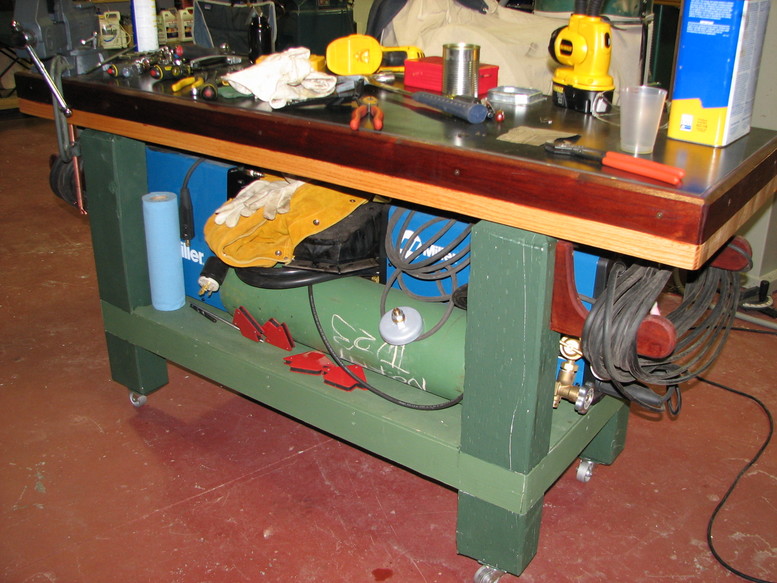 Well-organized workshop with workbench, drill press, bandsaw, and metalworking vices.