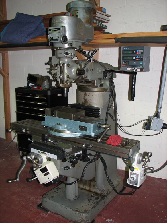 Heavy-duty metal milling machine with rotating table and various attachments on concrete floor.