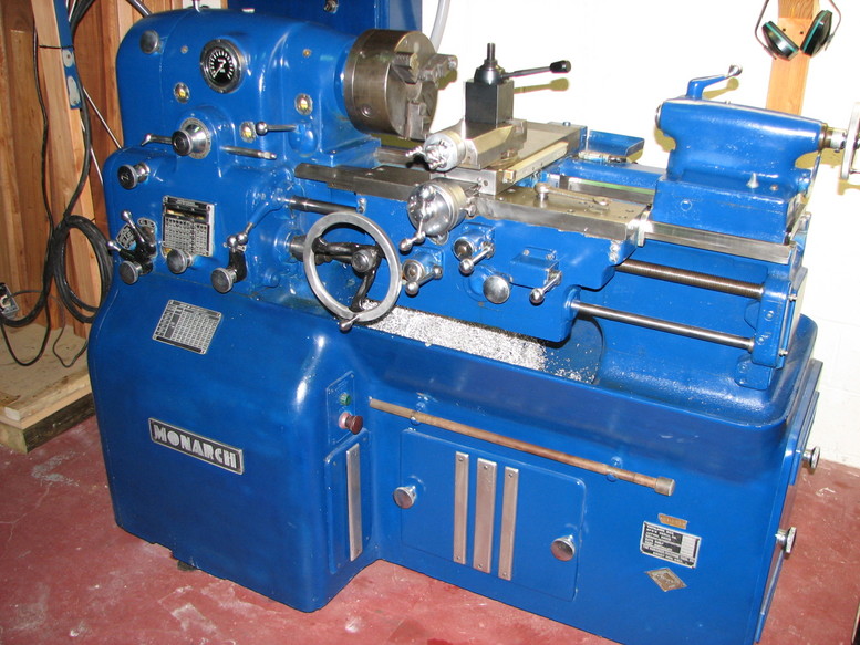 Blue metal lathe with tools and attachments on a workshop wall.