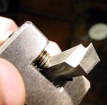 Metal wrench with bolt in jaws.