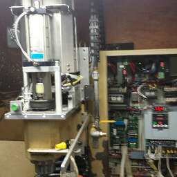 A large metal machine with various components and cables, set against a dark background.