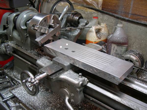 Metal lathe with attached large fly cutter on cluttered workbench.