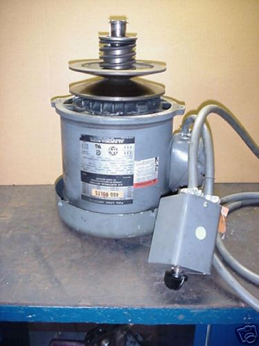 A cylindrical device with a pulley on top, situated on a blue surface.