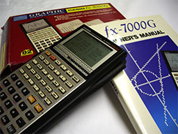 TI-30X IIS calculator on top of an f(x)-7000G graphing calculator manual.