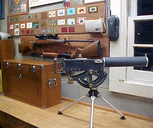 Large brown metal box with handle in front of a wall with framed pictures, next to a silver machine with flat top and buttons/knobs.
