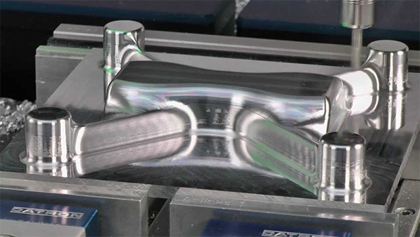 A shiny metal mold with four cylindrical protrusions.