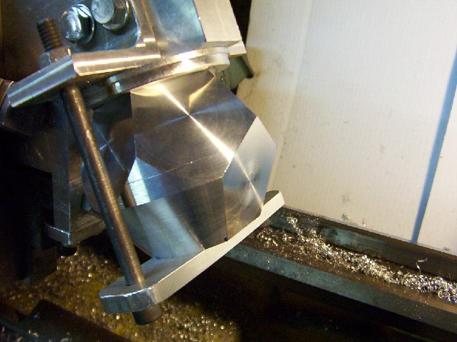 Metal milling machine fixture on a workshop table with debris.