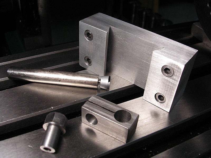 Metal parts on machine tool bed with slotted grooves.