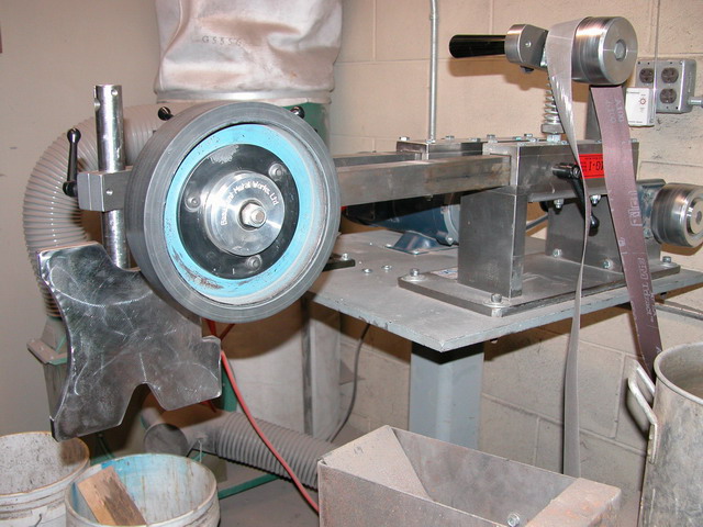 Metalworking lathe with large wheel and various tools.
