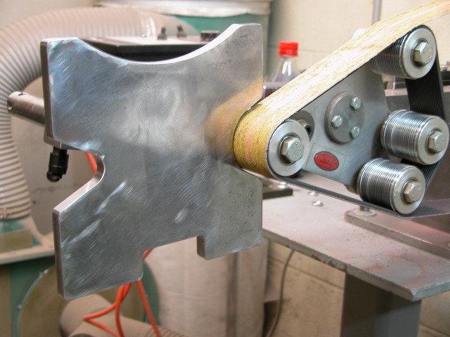 Metal device with cross-shaped cutout in machine shop setting.