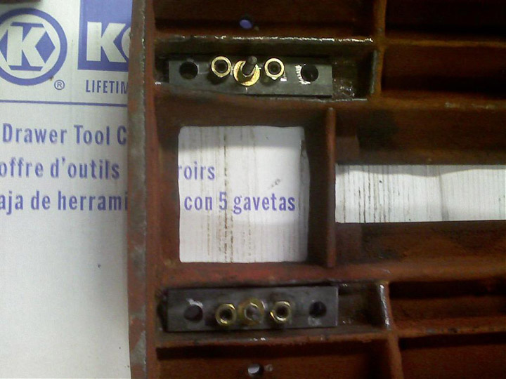 Old wooden cabinet with screws and storage unit label in English and Spanish.