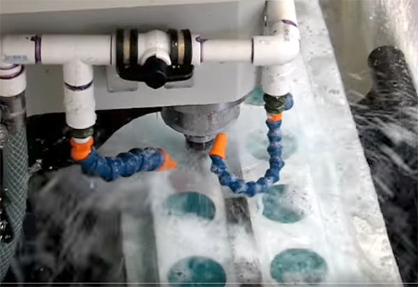 Close-up of a machine's cooling system with PVC pipes, blue hoses, and orange fittings.